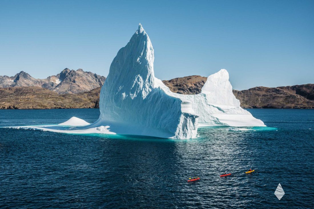Photo de kayakistes de mer devant un énorme Iceberg au Groenland