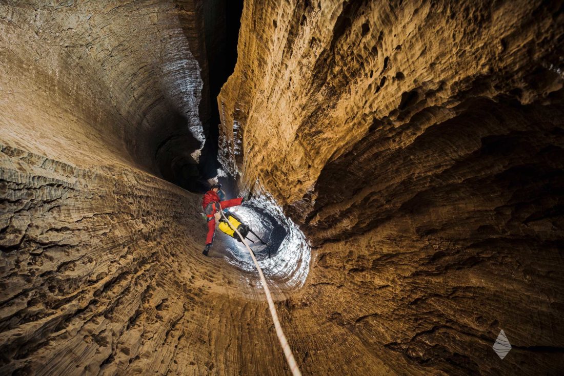 Photo d'un spéléologue descendant un puit dans la traversée de la grotte de La Diau